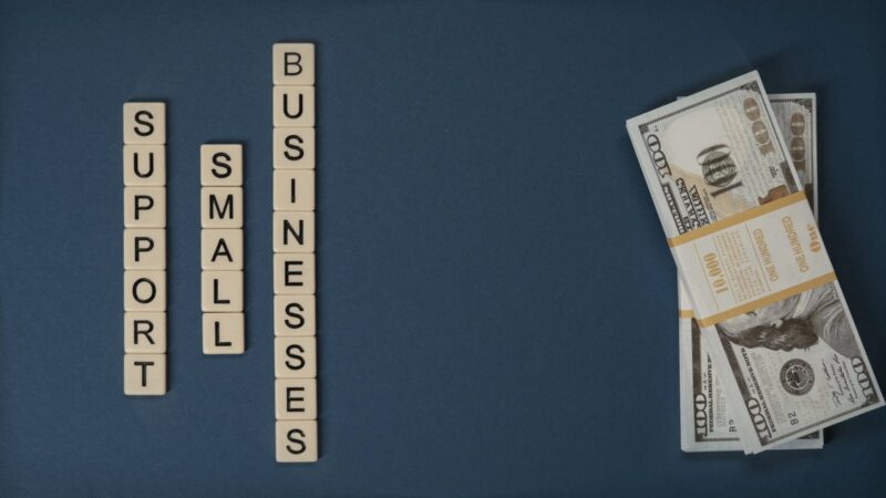 Conceptual image of supporting small businesses with financial resources using money and letter tiles.